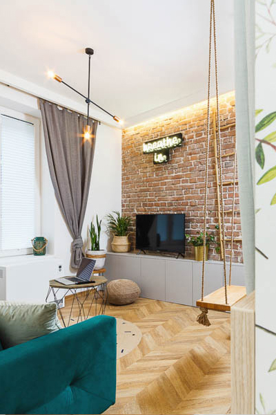 Salon z ceglaną ścianą oraz zieloną sofą